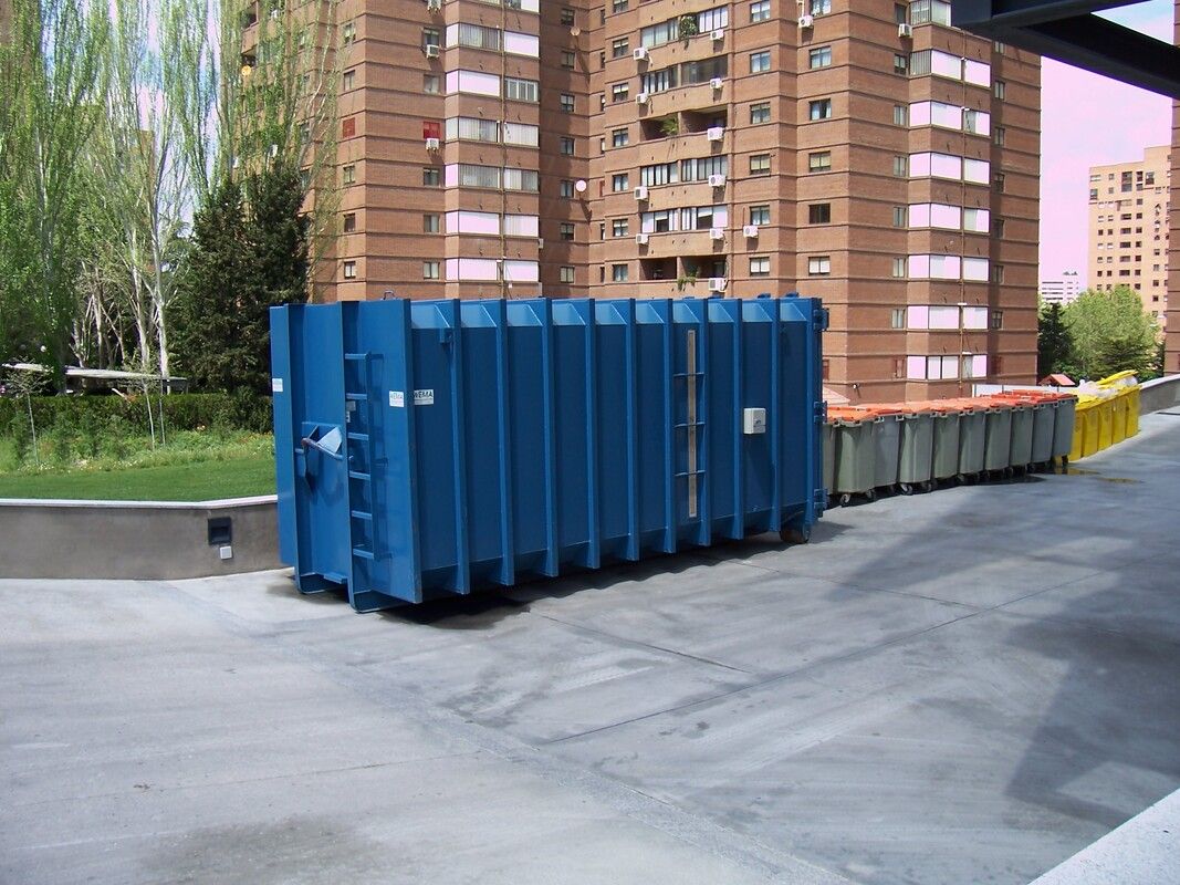 A large blue roll off dumpster outside a building